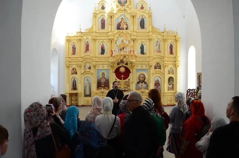 Группа молодых людей стоит у золочёного иконостаса Спасского храма